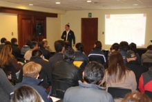 Agrónomo SAG dictando charla a agricultores en una sala con proyector.